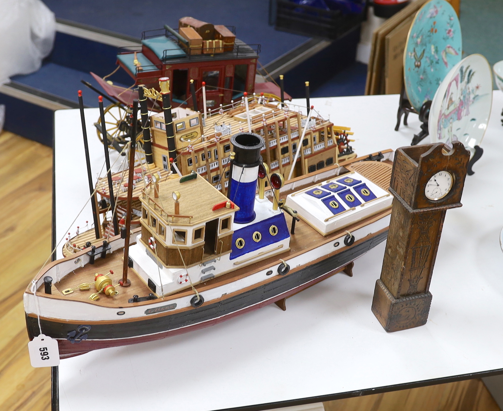 Two scratch built wooden model boats; a Mississippi style paddle steamer and a steam tug, together with a U.S. Western style coach plus a pocket watch and stand in the form of a long case clock, tug length 81cm